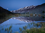 A full moon reflects off a pond in Sierra Nevada